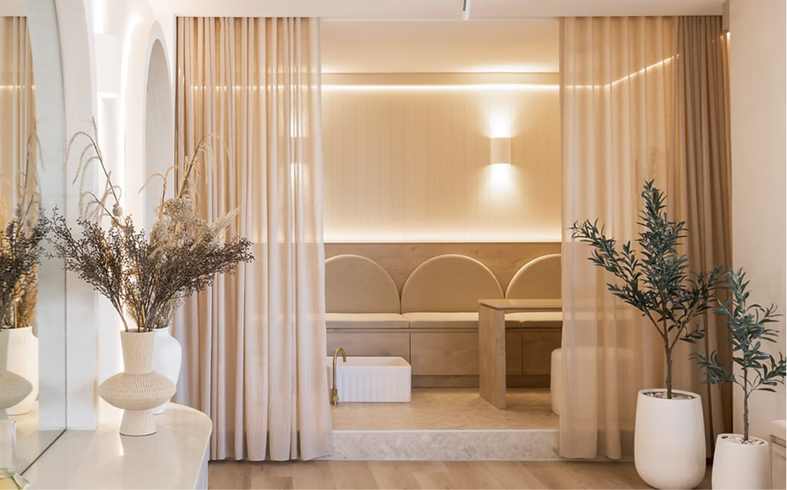 A softly lit treatment suite with a soaking tub and plants at GENEVA Med in Alpharetta