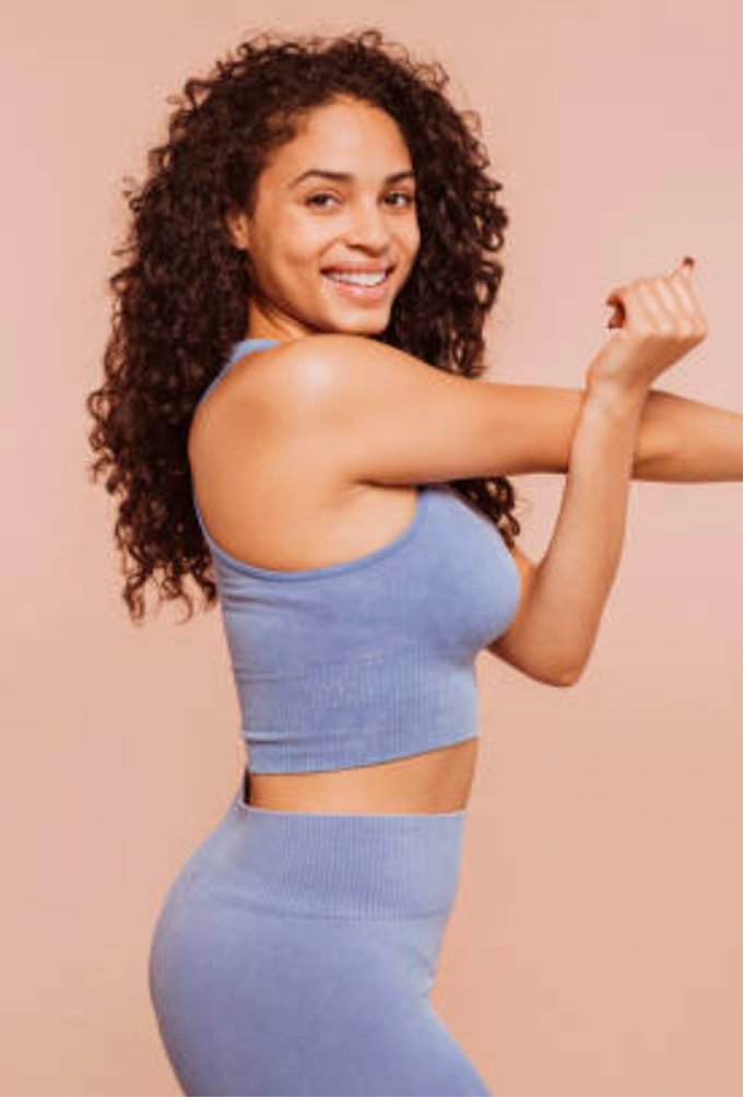 A woman stretching her arm across her chest after medical weight loss treatment