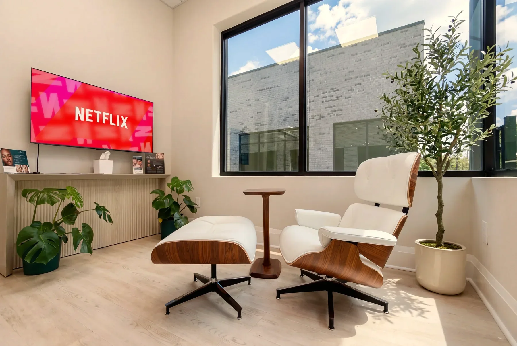 The GENEVA Med lounge with a white leather lounge chair, plants and a TV